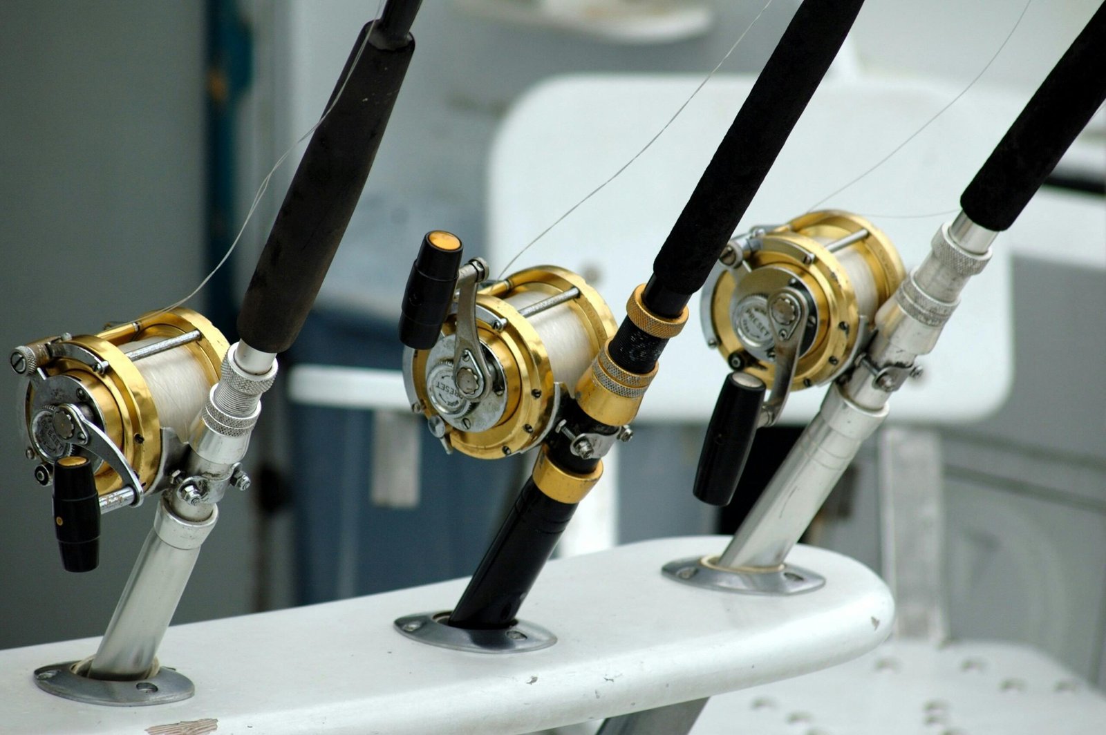 Detailed view of fishing rods with gold reels on a boat, ideal for angling enthusiasts.